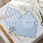 Blue baby shower invitation with striped envelope liners and baby's breath by Wrapped Studios.