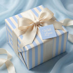 Luxury blue striped wrapping paper with a cream satin bow and "With Love" tag by Wrapped Studios.