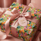 Luxury floral wrapping paper with a pink satin ribbon and "With Love" gift tag by Wrapped Studios.