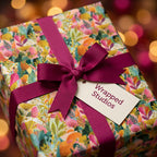 Vibrant botanical floral wrapping paper with a magenta ribbon bow and Wrapped Studios gift tag.