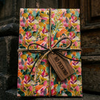 Colorful floral wrapping paper by Wrapped Studios on a gift with a twine bow and wooden "No Peeking" tag.