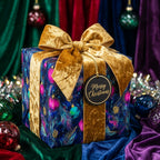 Luxury Christmas gift wrap with jewel-tone ornament pattern and gold velvet bow by Wrapped Studios.