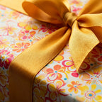 Floral wrapping paper with a golden ribbon bow, perfect for a birthday or special occasion gift.