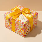Square gift wrapped in bright floral birthday wrapping paper with gold satin ribbon from Wrapped Studios.