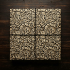 Square gift wrapped in luxury gold and black floral wrapping paper with twine, on dark wood.