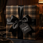 Luxury gift wrapped in brown plaid paper with a large black satin bow.