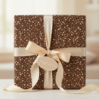 Brown birthday wrapping paper with polka dots and a cream-colored satin ribbon on a square gift box.