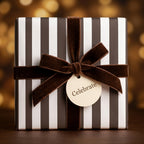 Luxury striped wrapping paper with a brown velvet bow and 'Celebrate' tag by Wrapped Studios.