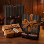 Luxury brown striped wrapping paper and velvet gift wrap with bows on a wood table by Wrapped Studios.