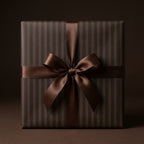 Brown striped luxury gift wrap with a satin bow on a gift box by Wrapped Studios.