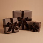 Elegant brown wrapping paper on square gift boxes with plush velvet ribbon bows for sophisticated presents.