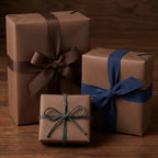 Three brown paper gift boxes wrapped with brown, blue, and gray twine ribbons on a wooden surface.