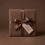 Elegant brown wrapping paper on square gift box with satin ribbon and gift tag.