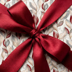 Elegant botanical Christmas gift wrap with a luxury red satin bow by Wrapped Studios.