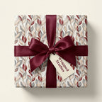 Elegant burgundy botanical wrapping paper with a luxury satin bow on a gift box by Wrapped Studios.