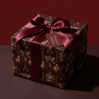 Luxury burgundy and gold Christmas wrapping paper by Wrapped Studios on a gift box with a satin ribbon bow.