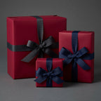 Burgundy gift wrap with navy and gray ribbon bows. Solid color wrapping paper for elegant birthdays or Christmas gifts.