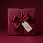 Burgundy gift box wrapped in solid color paper with satin ribbon bow, perfect for elegant holiday or birthday gift wrapping.