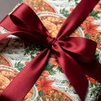 Seafood and music holiday wrapping paper tied with a red satin bow. Christmas gift wrap by Wrapped Studios.