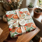 Festive gumbo and saxophone Christmas wrapping paper with cream silk ribbon by Wrapped Studios.