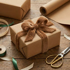 Kraft wrapping paper present with fluffy brown ribbon bow on rustic wooden table, plus green and beige ribbon.