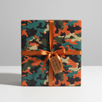 Square gift box in modern camo wrapping paper with an orange satin ribbon and gift tag.