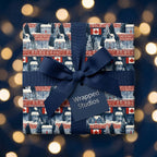 Canadian Christmas wrapping paper with winter cabins and a navy blue bow by Wrapped Studios.