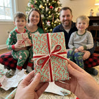 Candy cane wrapping paper with red ribbon by Wrapped Studios, held in front of a family at Christmas.