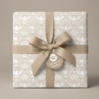 Baptism wrapping paper with white doves and chalices, tied with a beige ribbon bow by Wrapped Studios.
