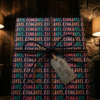Congrats wrapping paper with teal and pink text, twine bow, and well done tag by Wrapped Studios.