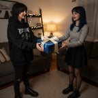 Woman gives a present wrapped in blue celestial-themed paper with a cream satin ribbon.