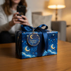 Elegant navy birthday wrapping paper featuring moons and stars, tied with a satin ribbon bow.