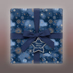 Square gift wrapped in blue celestial wrapping paper with gold accents and a navy bow.