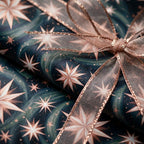 Luxury celestial starry wrapping paper in navy and rose gold with a sheer bow by Wrapped Studios.
