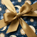 Celestial wrapping paper with a luxury sun and moon pattern and gold satin bow by Wrapped Studios.