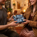 Celestial wrapping paper with gold suns and a blue satin bow on a gift held by a couple. Wrapped Studios.