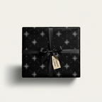 Elegant gift wrapped in black luxury wrapping paper with a silver star pattern and a black satin ribbon.