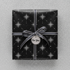 Elegant black gift box wrapped in starburst-patterned wrapping paper with a silver ribbon and "For You" tag.