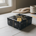 Black floral wrapping paper with gold twine on a square gift box.