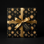 Luxury black and gold celestial wrapping paper with a gold satin bow by Wrapped Studios.