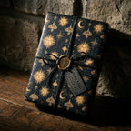 Luxury celestial gift wrap with gold sun and moon patterns on navy blue by Wrapped Studios.