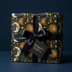 Celestial wrapping paper with gold sun and moon motifs and a black satin bow by Wrapped Studios.