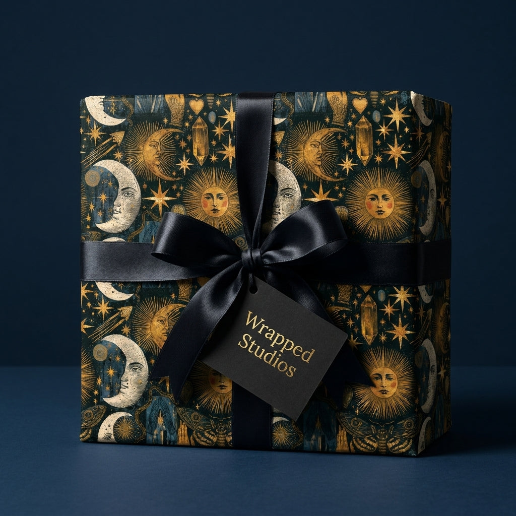 Celestial wrapping paper with gold sun and moon motifs and a black satin bow by Wrapped Studios.