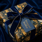 Luxury celestial wrapping paper with gold stars and a navy velvet bow, by Wrapped Studios.