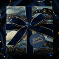Navy blue starry wrapping paper with gold details and velvet ribbon from Wrapped Studios.