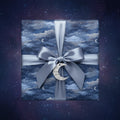 Elegant gift wrapped in blue celestial wrapping paper with moons and stars, finished with a silvery satin bow.