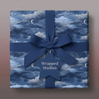 Square gift wrapped in celestial wrapping paper with navy ribbon and star tag.
