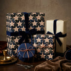 Luxury celestial star Christmas wrapping paper in navy and gold with velvet ribbons by Wrapped Studios.