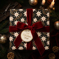 Luxury Christmas gift wrap with a star pattern and red velvet bow by Wrapped Studios.