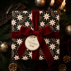 Luxury Christmas gift wrap with a star pattern and red velvet bow by Wrapped Studios.